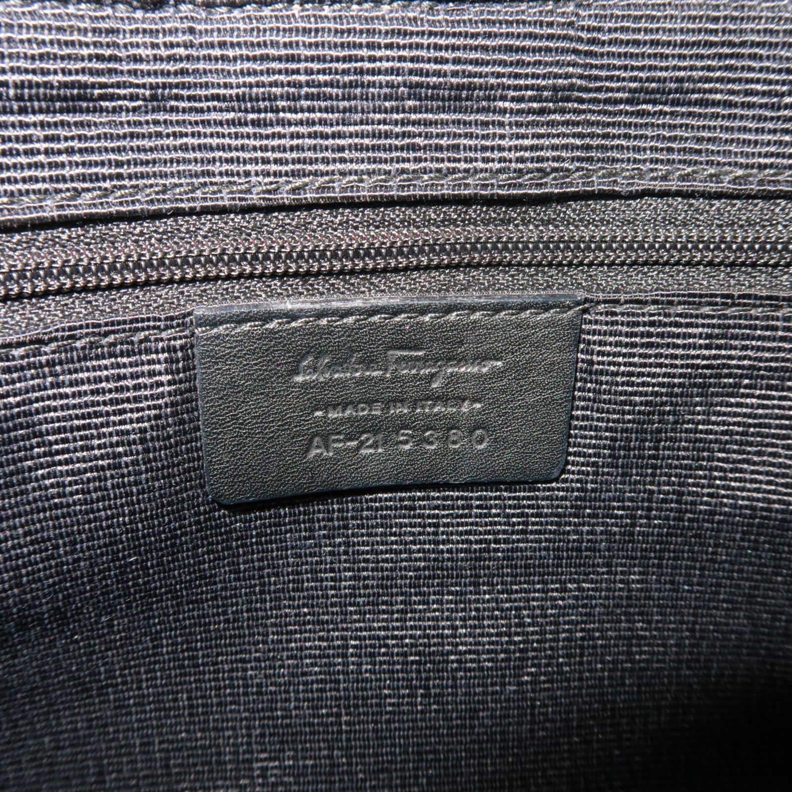 Interior label of Ferragamo Gancini Shoulder Bag Canvas Leather Black, showing serial number and care instructions.