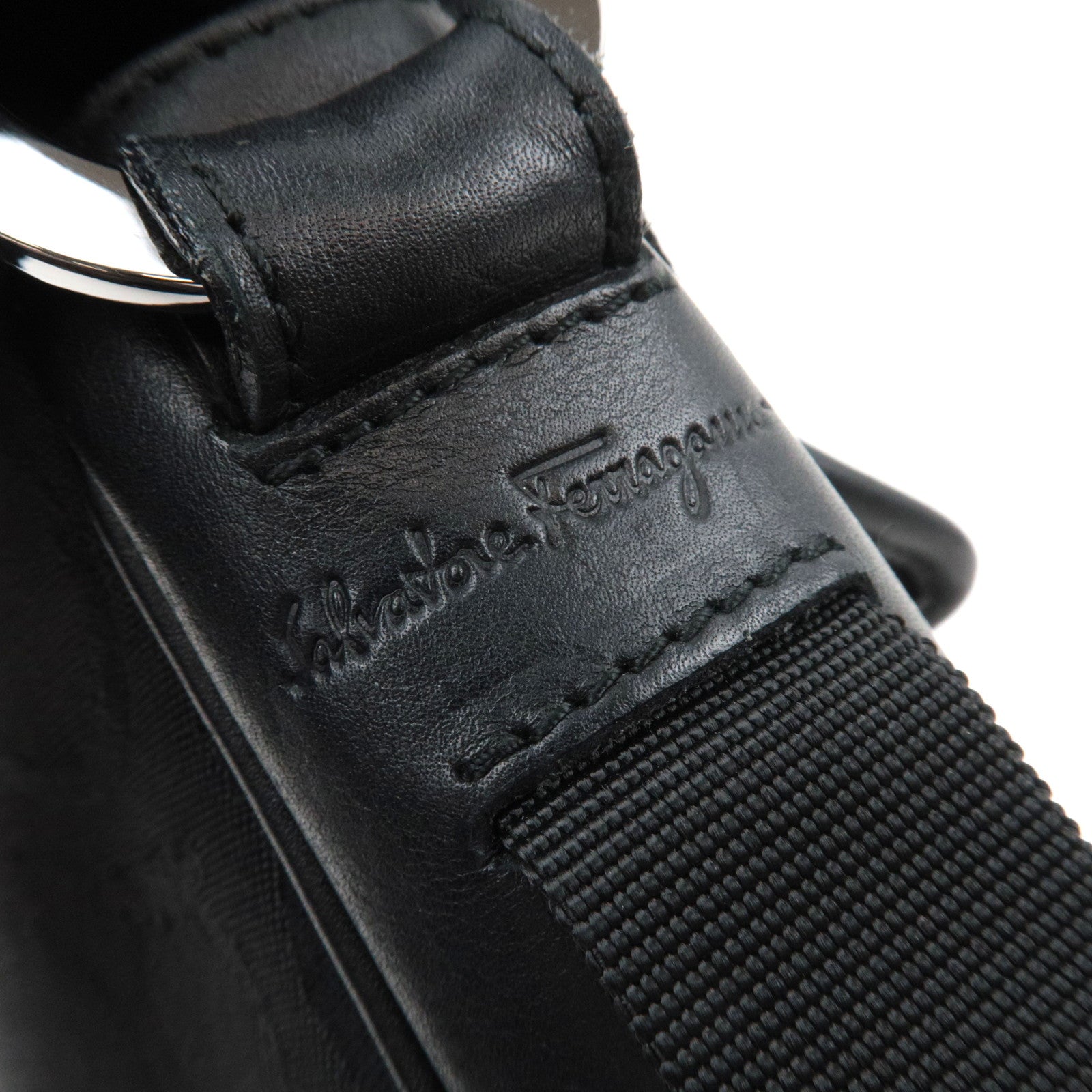 Close-up of Ferragamo Gancini Shoulder Bag Canvas Leather Black strap showcasing engraved logo and hardware details.